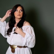 Woman in white dress against green wall